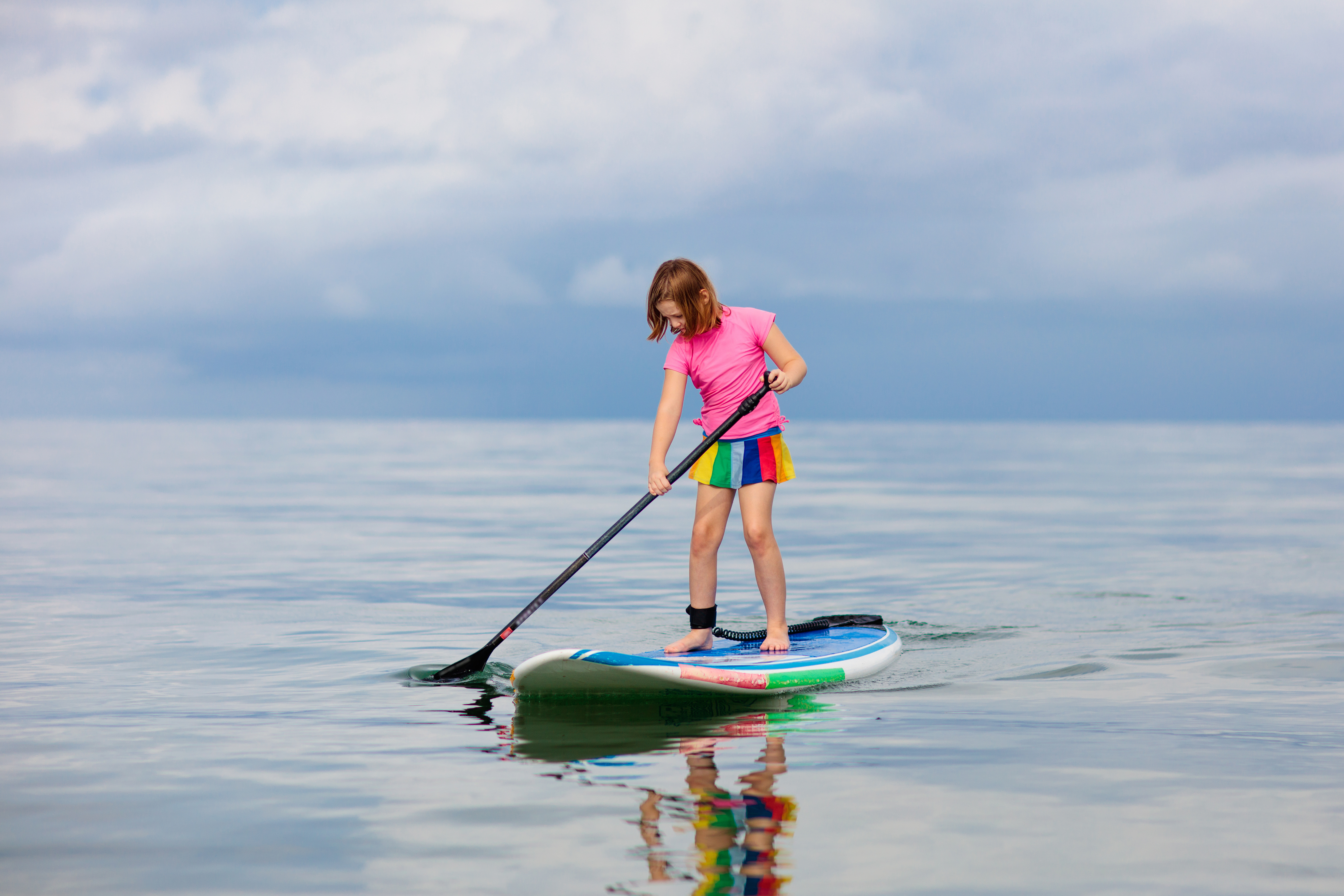 dítě s paddleboardem na vodě