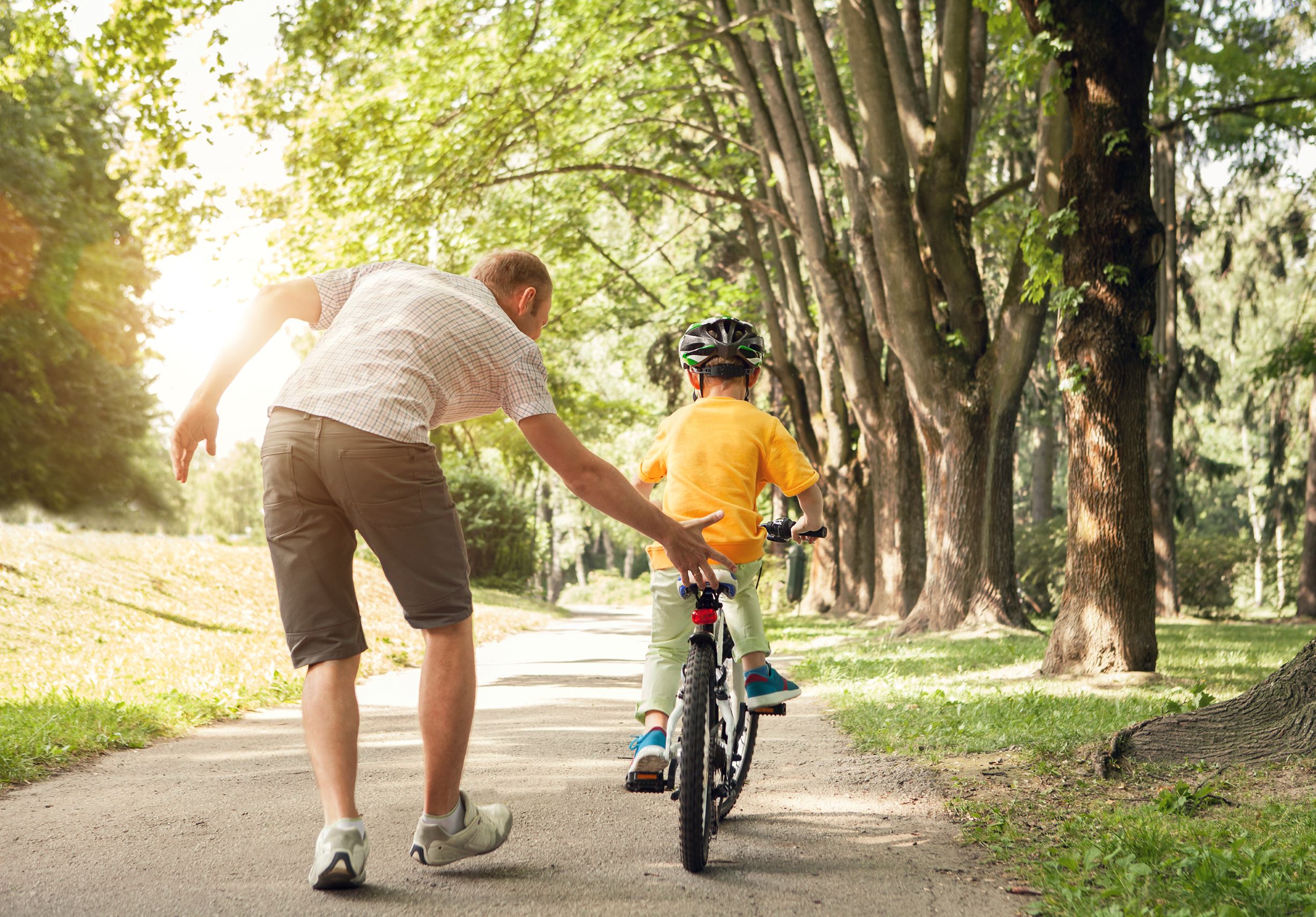 Un tată care își învață fiul să meargă cu bicicleta