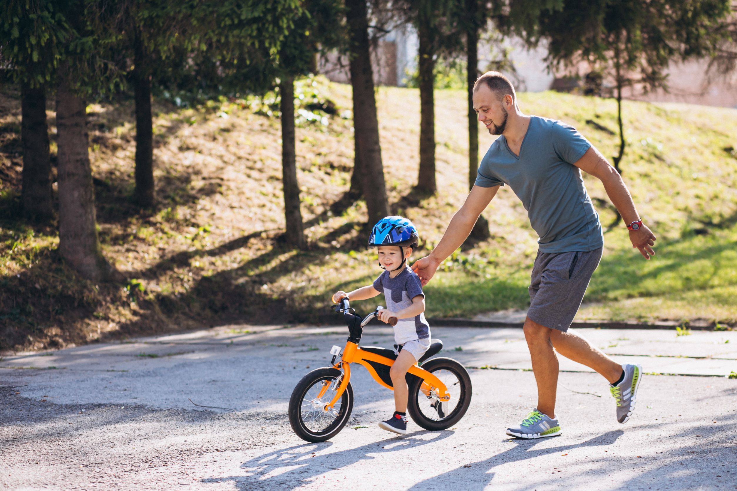 ojciec stopniowo uczy jeździć syna na rowerze bez pedałów