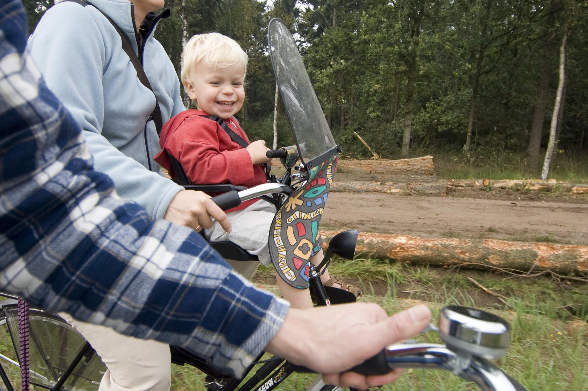 Chłopiec siedzący w foteliku rowerowym na przód  chroniony owiewką