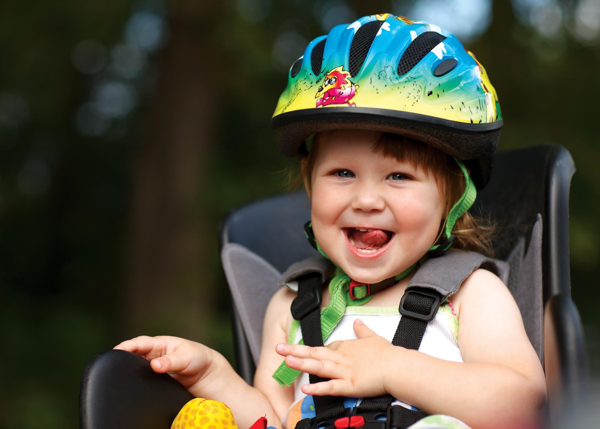 Une petite fille souriante dans un siège de vélo avec un casque