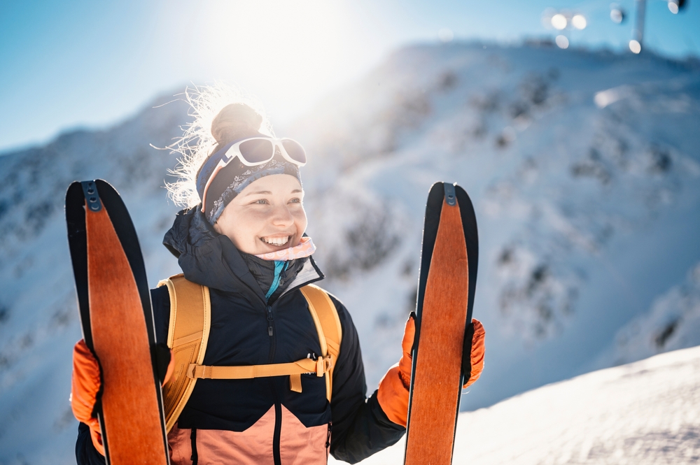 Una donna tiene in mano i suoi sci da scialpinismo con le cinghie incollate