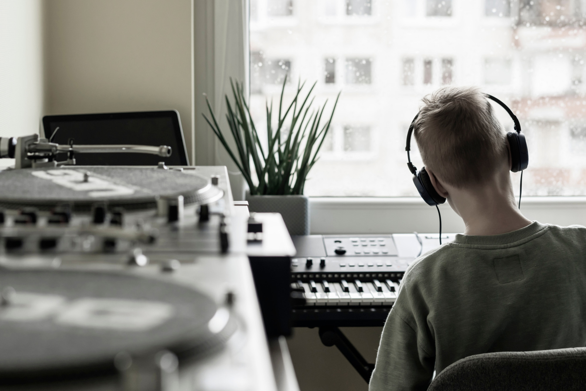 Ein Junge mit Kopfhörern spielt auf dem Keyboard