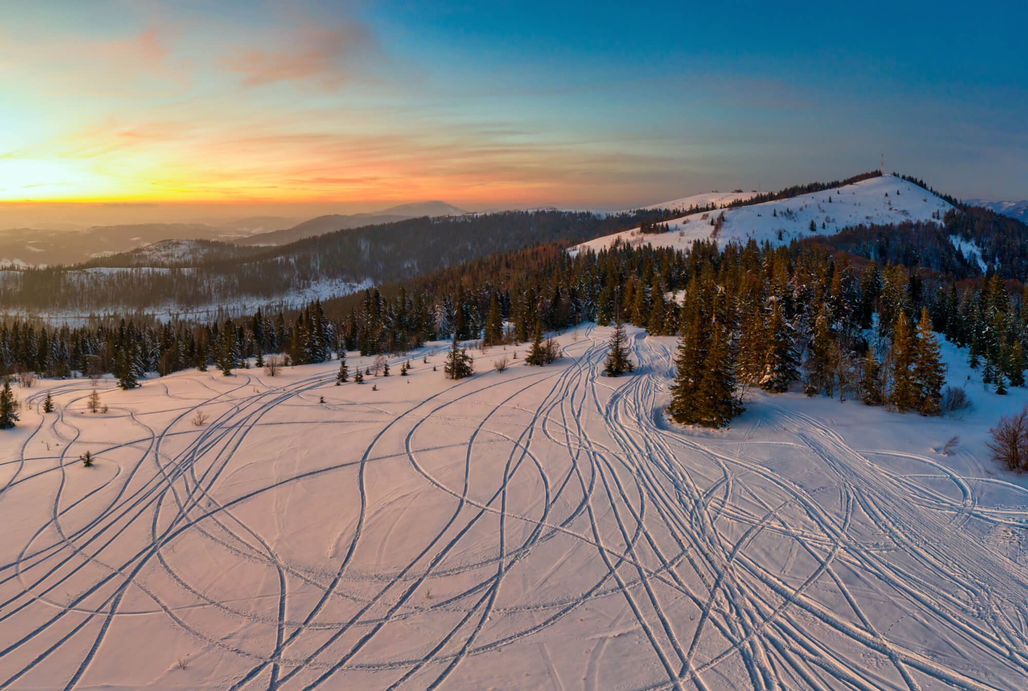 Zăpadă proaspătă brăzdată de piste arcuite ale schiorilor
