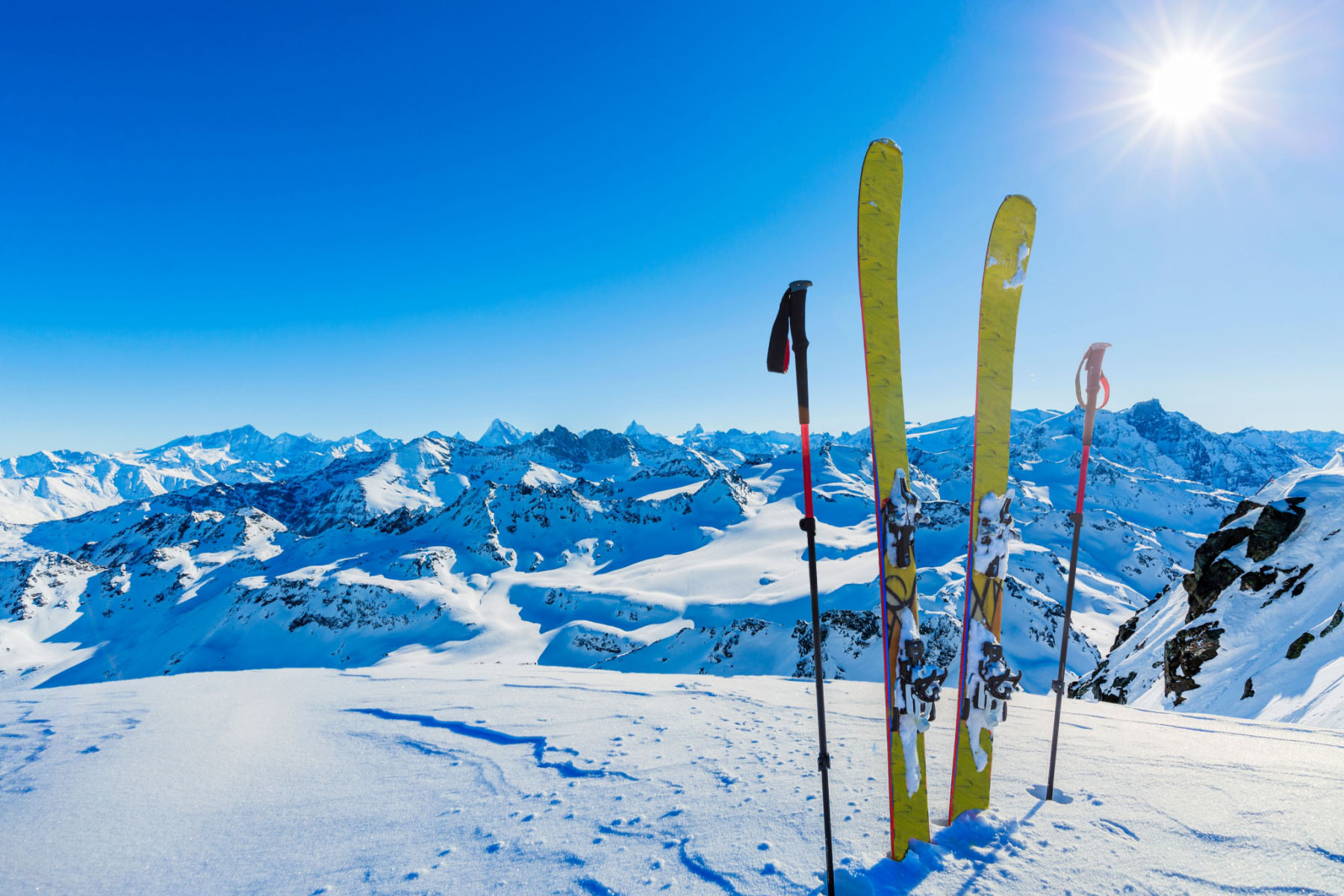 Ski touring gear in snow with mountain peaks in a background