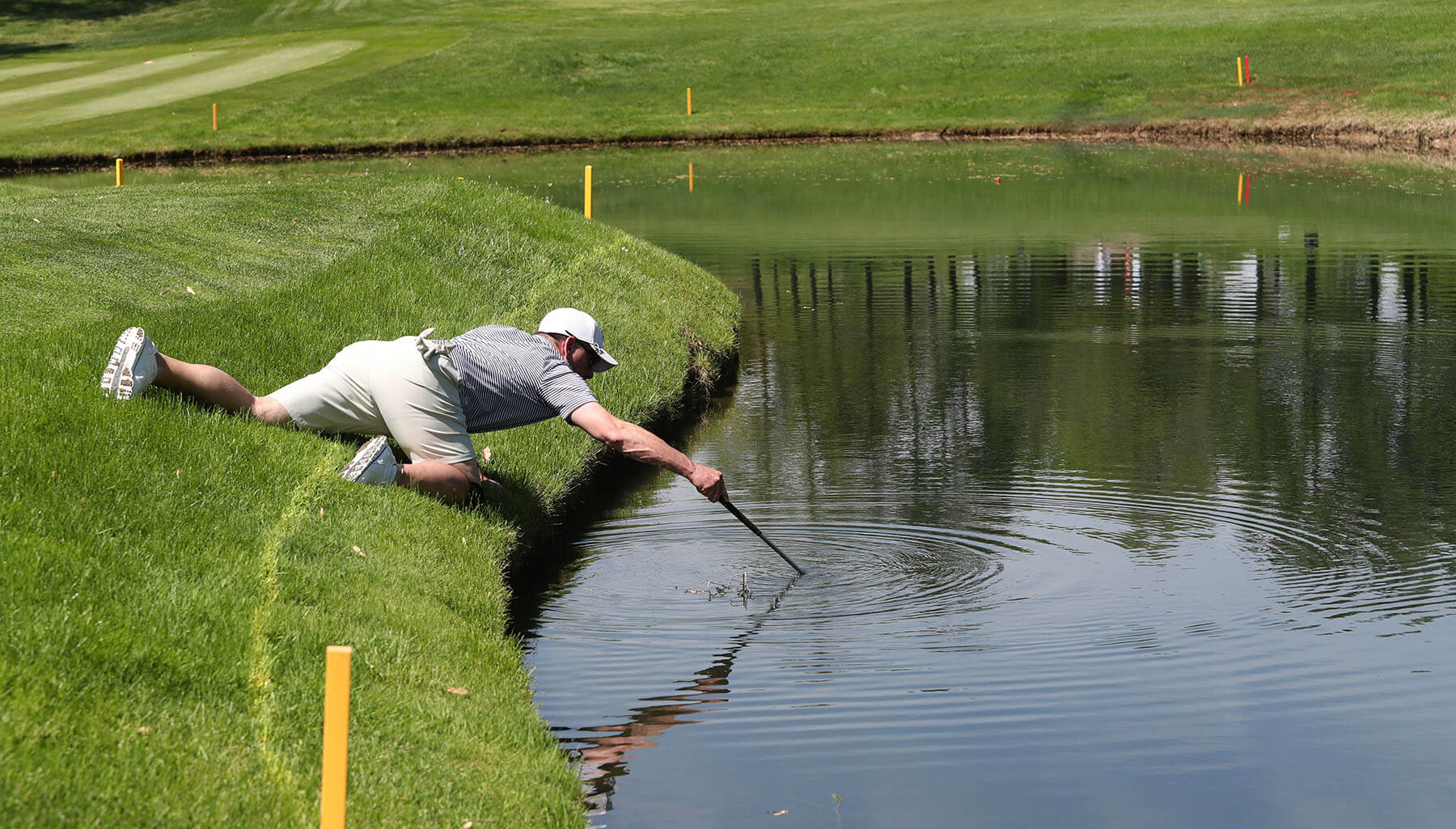 A player looking for a drowned golf ball in a water hazard