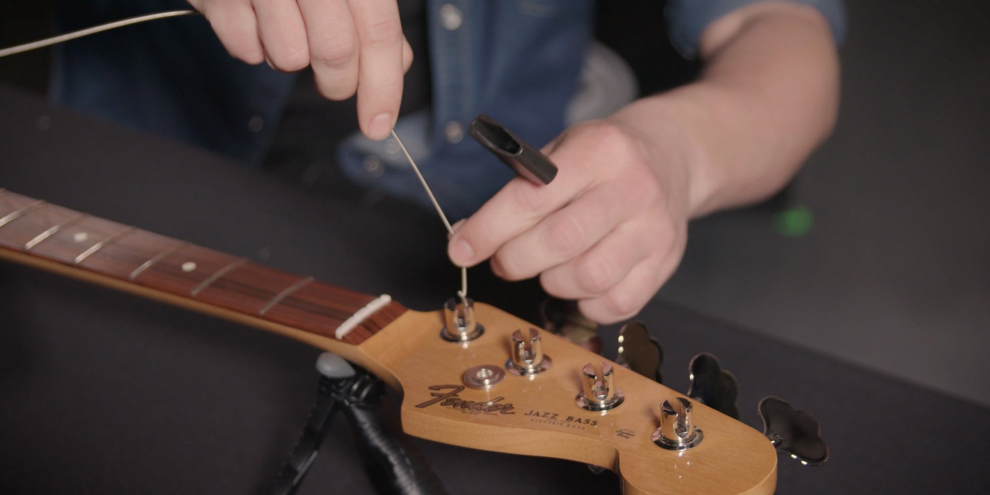 Threading a bass guitar string into the opening of the tuning post