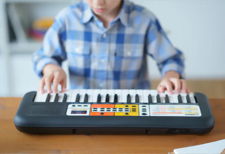 ein kleiner Junge spielt das Kinder-Keyboard Yamaha PSS-F30