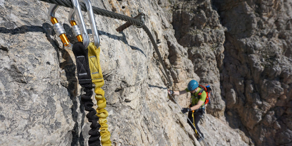 Carabiners of the via ferrata set hooked to the safety metal cable